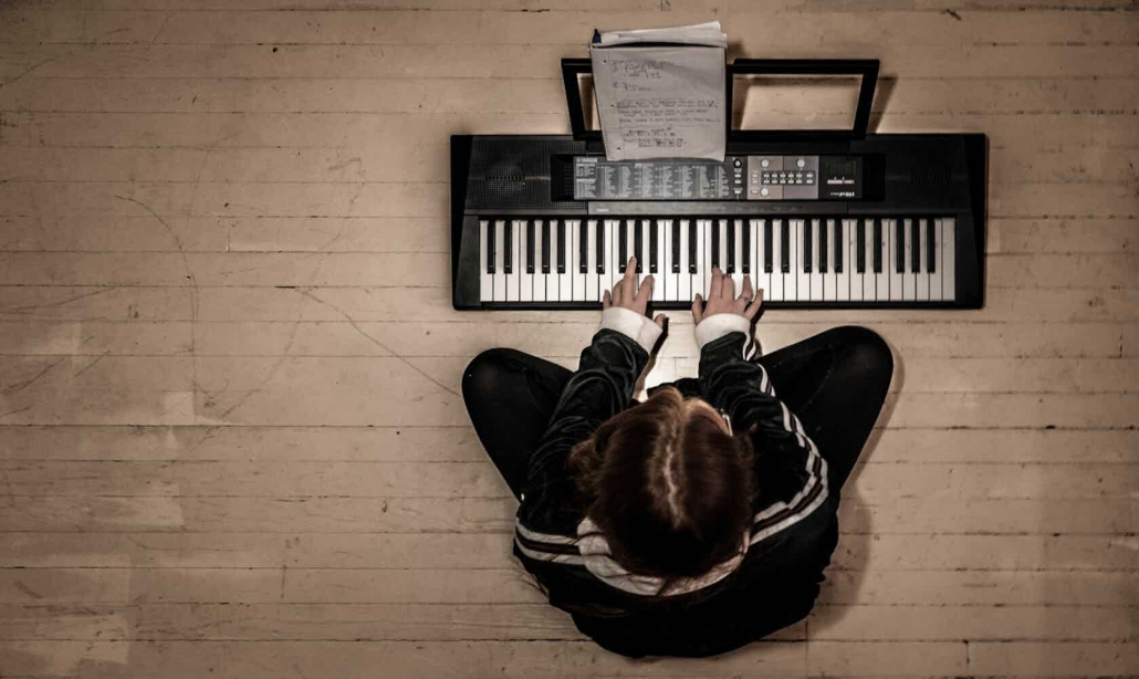 man playing a digital (midi) keyboard on a wood floor